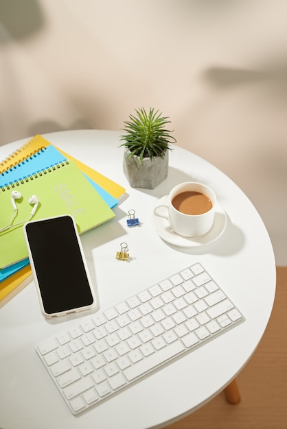 Mesa de mesa de escritório de vista superior. Espaço de trabalho com telefone móvel e material de escritório em fundo branco.