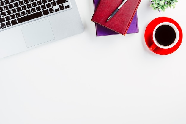 Mesa de mesa de escritório moderno branco com laptop, caneta, caderno e xícara de café. Vista superior com co