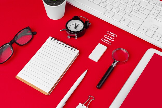 Mesa de mesa de escritório vermelho com caderno em branco, teclado e suprimentos. vista superior com espaço de cópia. postura plana.