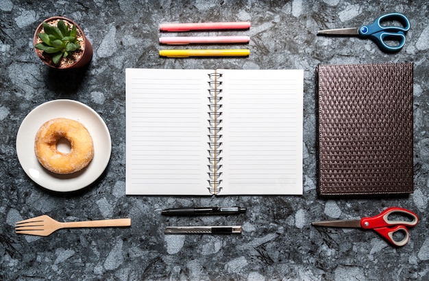 Mesa de mesa de mármore de escritório com livro, suprimentos, donut e xícara de leite.