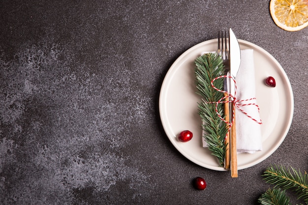 Mesa de Natal com um prato, garfo, faca, galhos de árvores de Natal e enfeites de Natal. vista superior, copie o espaço