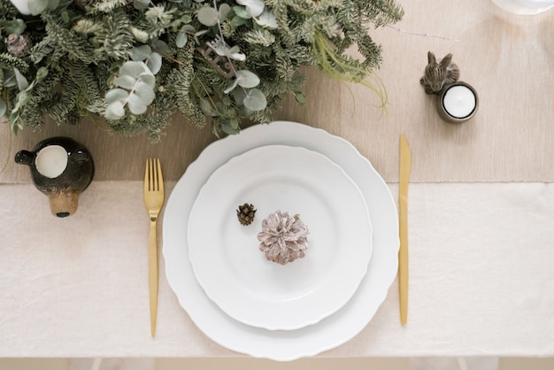 Foto mesa de natal elegante com dois pratos brancos colocados um em cima do outro, em cima deles