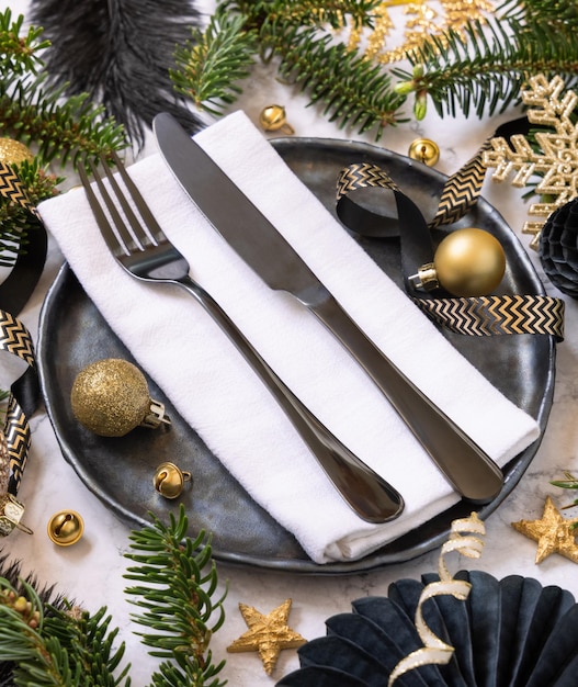 Mesa de Natal preta e dourada com decorações e galhos de árvores de abeto fecham