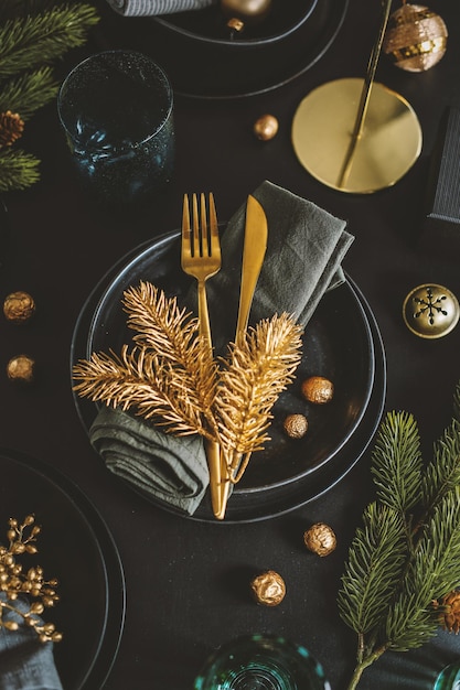 Mesa de natal servida em tons escuros com decoração dourada.