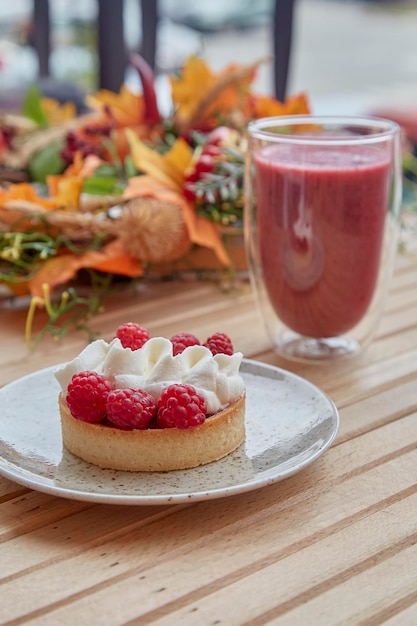 Mesa de outono saudável e estética brilhante, smoothie de morango rosa e torta francesa no terraço do lado de fora