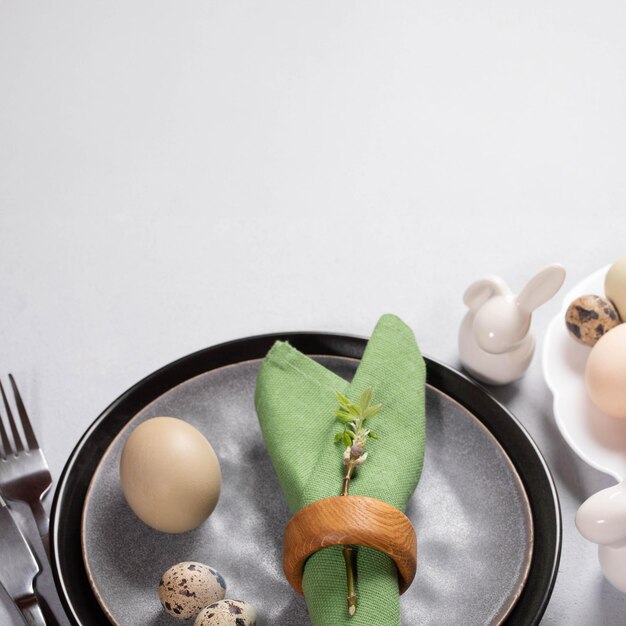 Mesa de Páscoa em cores naturais de moda Pratos cinzentos guardanapo verde ovos orgânicos coelhos de cerâmica