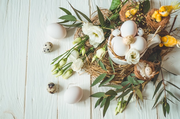 Mesa de Páscoa feliz Ovos de Páscoa em um copo em uma mesa de madeira branca com decoração floral. Feliz Páscoa conceito