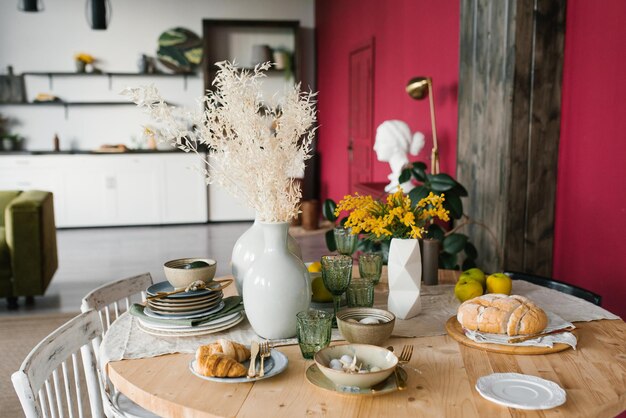 Foto mesa de páscoa festiva com flores de mimosa em um vaso e ovos de comida tradicional o interior