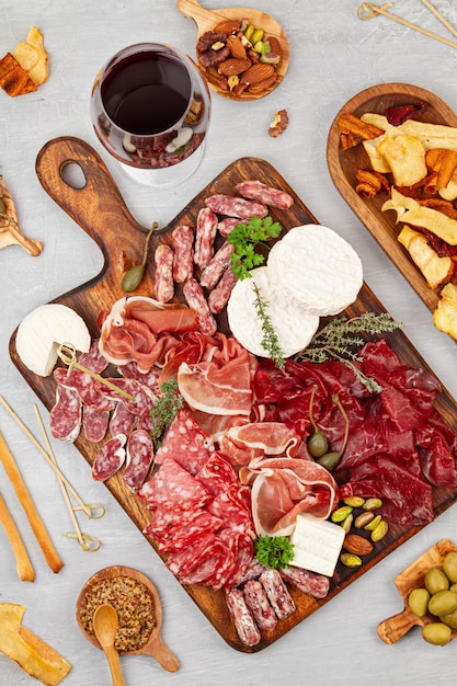 Mesa de petiscos com diferentes antepastos, charcutaria, petiscos e vinhos. Salsichas, fiambre, tapas, azeitonas, queijos e bolachas para buffet. Vista superior, configuração plana