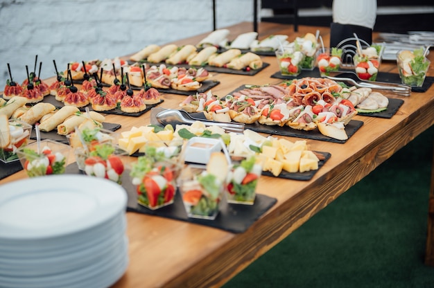 Mesa de recepção buffet com hambúrgueres, salgadinhos frios, carnes e saladas