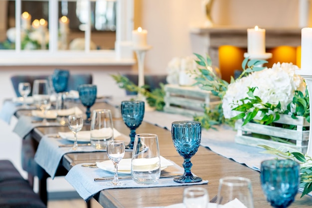 Mesa de restaurante com flores de vidro azul e velas decoradas para festa de casamento