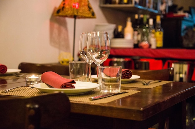 Mesa de restaurante elegante com talheres, louças e copos.