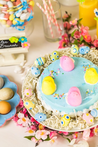 Mesa de sobremesa com bolo de Páscoa decorada com tradicionais garotas de marshmallow de Páscoa.