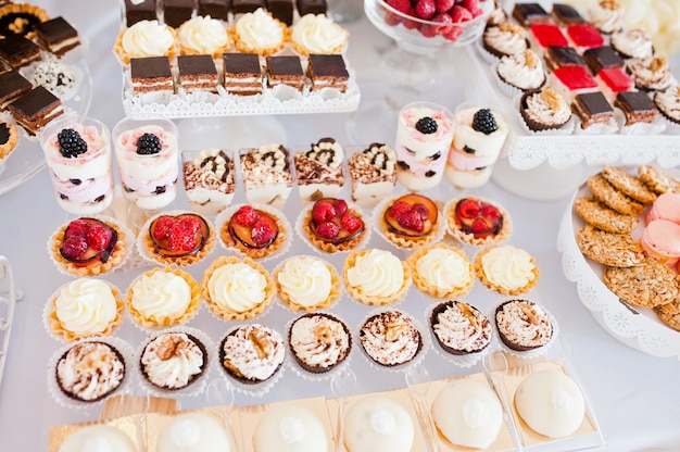 Mesa de sobremesa de deliciosos doces na recepção do casamento.