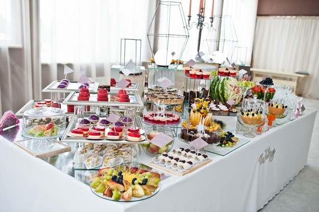 Mesa de sobremesa de deliciosos doces na recepção do casamento.