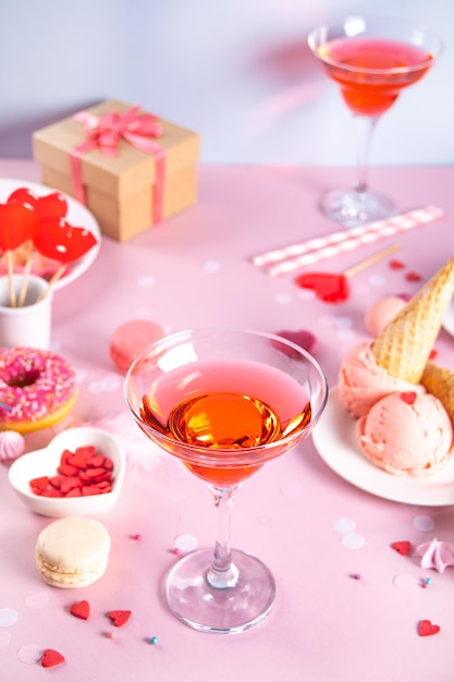 Mesa de sobremesa doce romântica com copo de vinho rosa waffles rosquinha sorvete macaron pirulito doces conceito de dia dos namorados