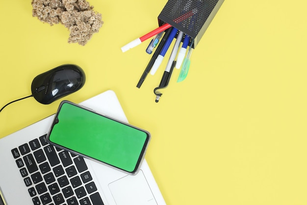 Mesa de trabalho cheia de artigos de papelaria isolada em fundo amarelo