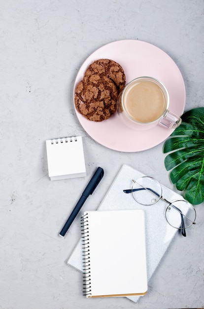 Mesa de trabalho cinza com notebooks, espaço em branco vazio, suprimentos, copos e xícara de café