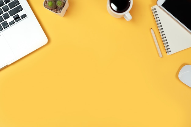 Mesa de trabalho com computador e material de escritório em amarelo