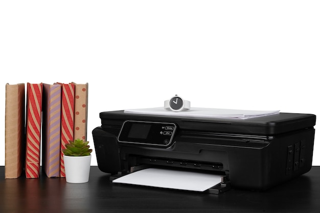 Mesa de trabalho com impressora e livros empilhados no fundo branco