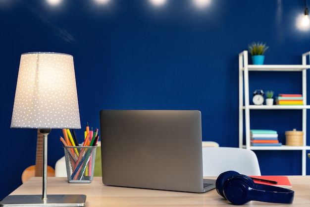 Mesa de trabalho com laptop contra parede azul no apartamento moderno