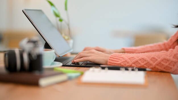 Mesa de trabalho com mãos femininas digitando no teclado do computador tablet trabalhando em casa