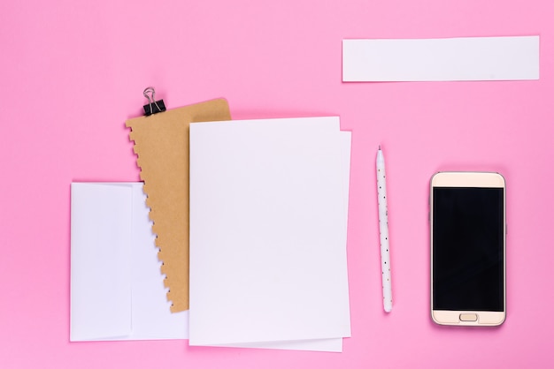 Mesa de trabalho com smartphone e notebook com copyspace em fundo rosa, estilo minimalista plana leigos