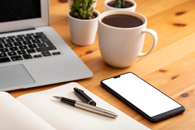 Mesa de trabalho de madeira com material de escritório e café do smartphone do computador portátil