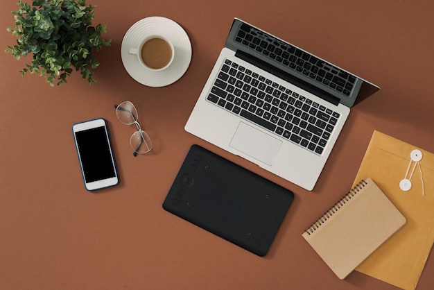 Mesa de trabalho do fotógrafo com câmera, laptop, tablet e computador na mesa marrom