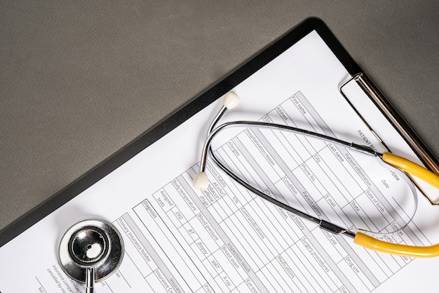 Mesa de trabalho do médico de medicina. Perfil do paciente e estetoscópio em cima da mesa.