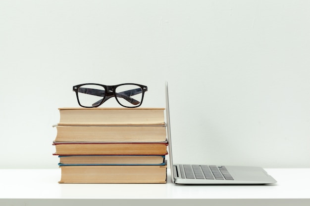 Mesa de trabalho. Laptop aberto, livros e outros materiais de escritório