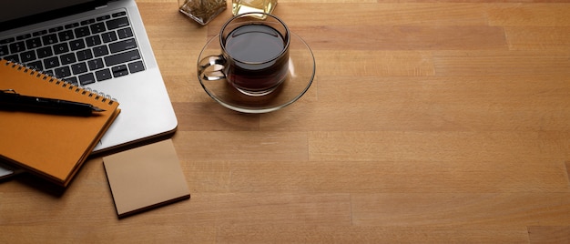 Mesa de trabalho na moda com espaço de cópia, laptop, xícara de café e artigos de papelaria na mesa de madeira