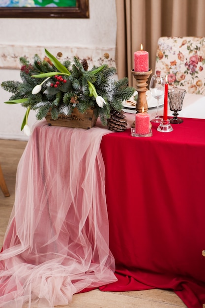 Mesa decorada con velas y ramas de abeto. Decoración de la cena de navidad.