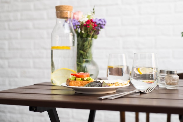 La mesa con desayuno de bocadillos y huevos fritos vasos de agua con limón