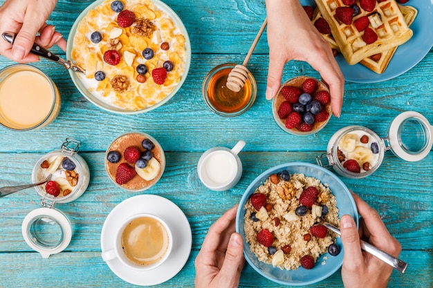 Mesa de desayuno con gofres, avena, cereales, café, jugo y bayas frescas.