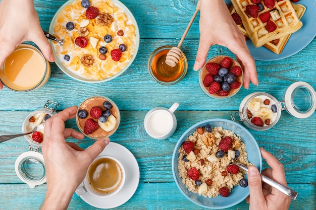 Mesa de desayuno con gofres, avena, cereales, café, jugo y frutos del bosque frescos. Desayuno saludable