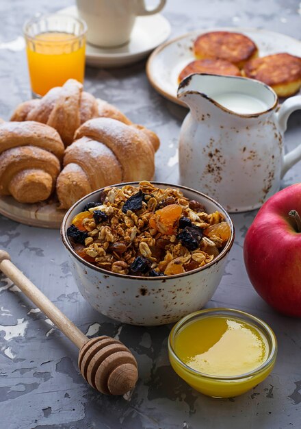 Mesa de desayuno con granola, croissants, manzana, café, zumo.