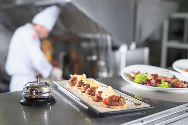 La mesa de distribución en la cocina del restaurante. El chef prepara una comida en el fondo de los platos terminados.