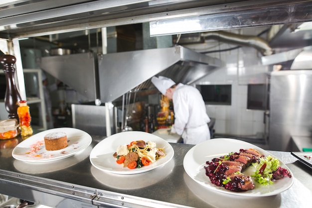 La mesa de distribución en la cocina del restaurante. El chef prepara una comida en el fondo de los platos terminados.