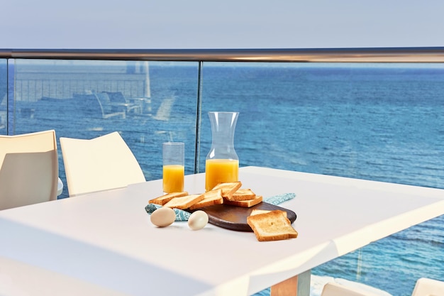 Mesa para dos servida con desayuno en el balcón exterior del hotel con vistas al mar