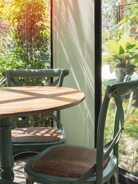 Mesa e cadeira de madeira vintage na sala de vidro perto do jardim