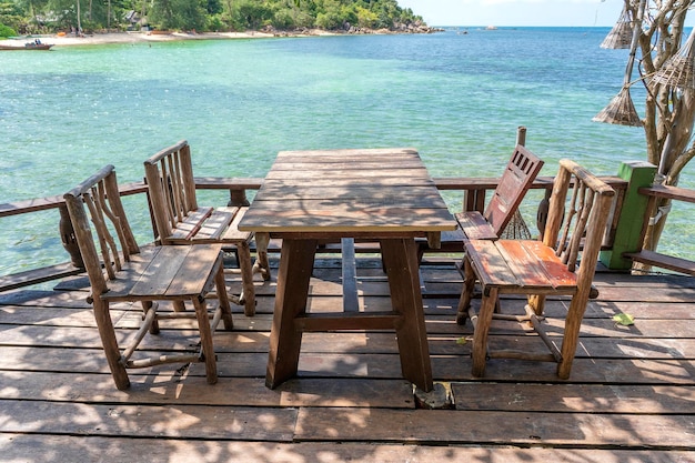 Mesa e cadeiras de madeira no café de praia vazio ao lado da água do mar. fechar-se. ilha de koh phangan, tailândia