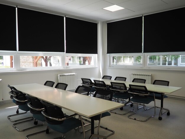 Mesa e cadeiras na sala de reuniões no escritório na sala de aula ou no salão da biblioteca Tintas brancas pretas e cinzas no interior Persianas pretas para escurecer a sala Design de interiores moderno