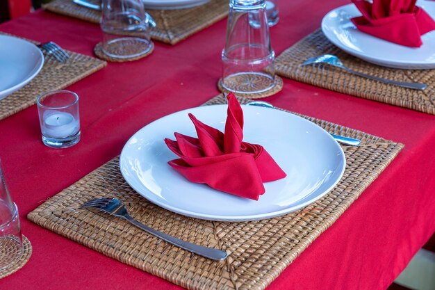 Mesa elegante com garfo colher prato branco e guardanapo vermelho no restaurante bela mesa de jantar com talheres e guardanapos arranjados