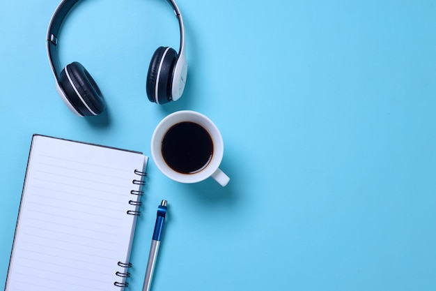 Mesa de escritorio azul en el lugar de trabajo con una taza de café en blanco y auriculares Vista superior con espacio para