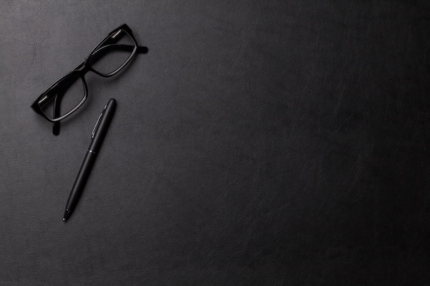 Mesa de escritorio de cuero de oficina con gafas y bolígrafo