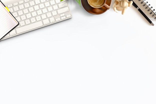 Mesa de escritorio de madera blanca de oficina con teclado, equipo de oficina y taza de café.