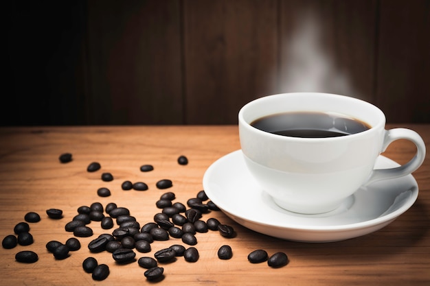 Mesa de escritorio de madera con café. Granos de café y taza de café en el espacio de madera con espacio de copia.