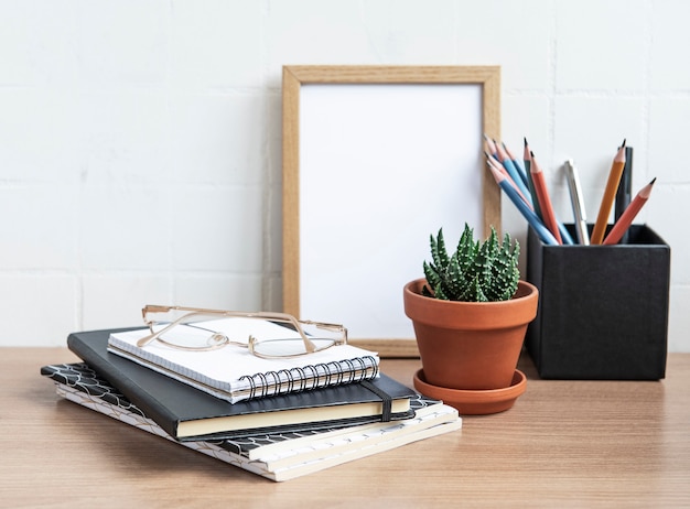 Mesa de escritorio de oficina con cuadernos, suministros y plantas de interior.