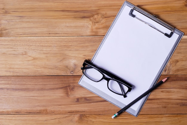 Mesa de escritorio de oficina con gafas corta papel de carta, bolígrafo y teléfono inteligente.